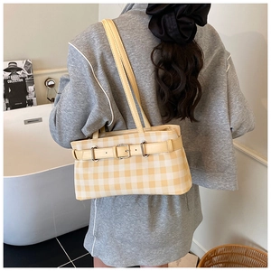 Detail of yellow checkered shoulder bag with metal buckle and slim leather straps