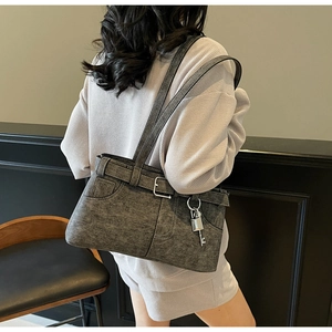 Detail of dark grey textured shoulder bag featuring silver buckle and metal charms