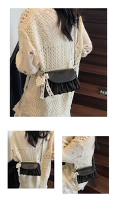 Detail of black pleated crossbody bag with metal chain strap and pearl heart charm
