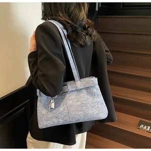 Detail of light blue denim tote bag with silver lock charm on wooden stairs background