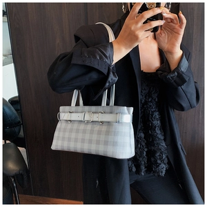 Detail of grey plaid shoulder bag with silver buckle strap and classic checkered pattern