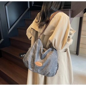 Detail view of a charcoal gray hobo bag in textured fabric with brown leather logo patch