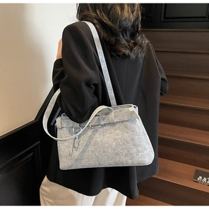 Close-up of light blue denim tote bag with buckle belt and vintage metal padlock charm