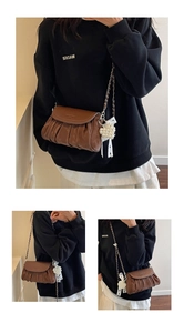 Close-up of brown pleated crossbody bag featuring chain strap and pearl bow charm detail