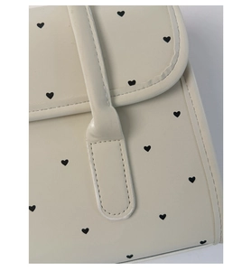 Detail of off-white PU leather bag featuring black heart prints and fine stitching quality