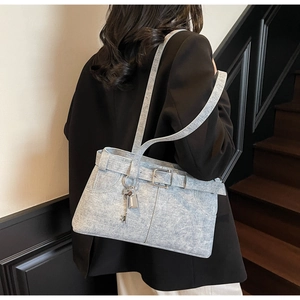 Detail of grey denim armpit bag with metal buckle and vintage lock charm accessory