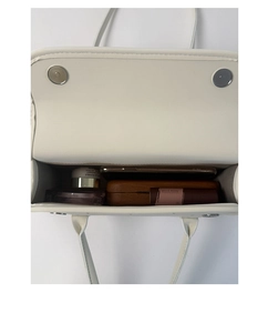 Interior view of white leather shoulder bag showing spacious storage and magnetic snaps