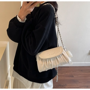 Detailed view of white pleated cloud bag with silver chain strap and pearl pendant