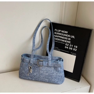 Detail view of light blue denim shoulder bag with vintage buckles and metal lock charm