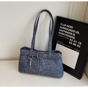 Detailed view of blue denim handbag with decorative buckle and metal key pendant accessory