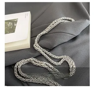 Detail of silver metallic braided chain strap on a textured gray fabric background