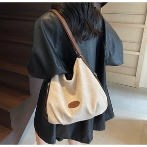 Close-up of beige corduroy tote bag with brown leather logo patch and handle details