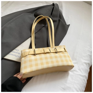 Detail of yellow checkered tote bag featuring a decorative belt and silver metal buckle