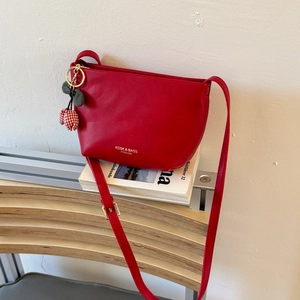 Detail of red leather tote bag with cherry charm resting on white books