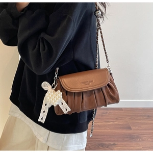 Detail of brown pleated cloud bag with silver chain strap and pearl heart charm