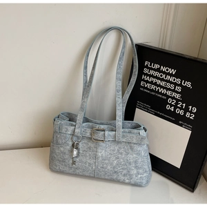 Detail of light blue denim baguette bag featuring silver key pendant and buckle design
