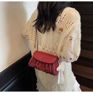 Detail of red pleated cloud bag featuring silver chain strap and pearl charm detail