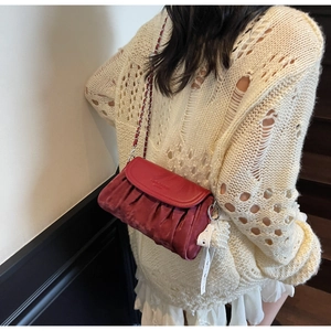 Macro shot of burgundy pleated crossbody bag with metal chain strap and pearl charm
