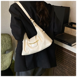 Detail of a cream crescent underarm bag featuring a stylish golden metal clasp closure