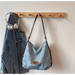 Detail of light blue tote bag with brown leather straps and Banatu logo patch