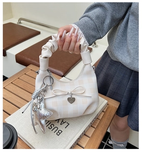 Detail of checkered handbag with bow, pleated handle and silver star pendant accessory