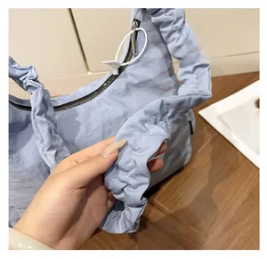 Close-up of light blue pleated nylon shoulder bag showing soft ruffled texture and zipper