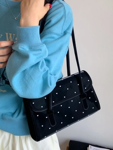 Summer black patent leather shoulder bag with white heart print worn by a model