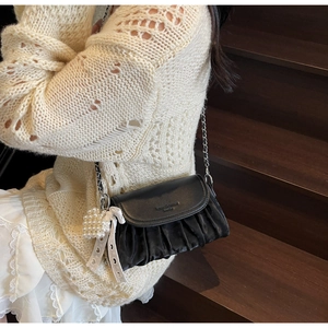 Close-up of black pleated cloud bag with silver chain strap and pearl heart charm