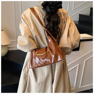 Detail of a brown glossy hobo bag with a gold metallic buckle on pleated faux leather