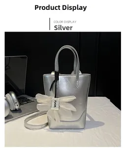 Detail of silver tote bag featuring a decorative white ribbon and fashion logo text