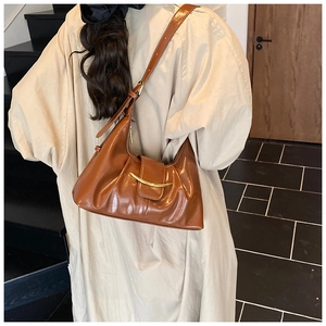 Caramel brown hobo bag with gold buckle shown on beige trench coat for office commute