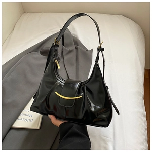Detailed macro view of the glossy black underarm bag with crescent gold hardware