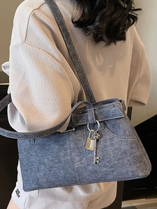 Blue denim tote bag with contrast stitching and silver lock charms on model's shoulder
