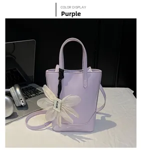 Detail view of purple tote bag with white floral ornament and long shoulder strap