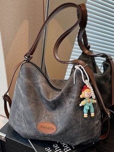 Deep grey canvas hobo tote bag with brown adjustable strap and cartoon pendant accessory
