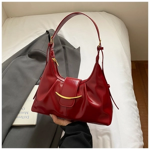 Detailed macro view of dark red glossy leather underarm bag with gold metal buckle