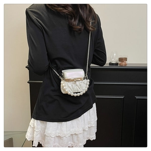 Close-up of a white quilted mini bag featuring large pearl decorations and silver chain