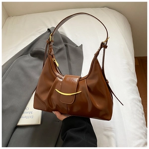 Close-up of caramel leather underarm bag with pleated design and gold crescent buckle