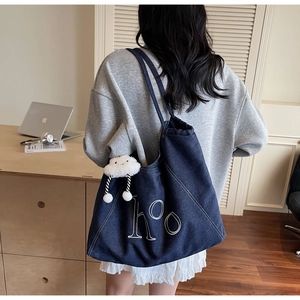 Détail du cabas en denim bleu avec broderie 'hoo' blanche et breloque nuage en peluche