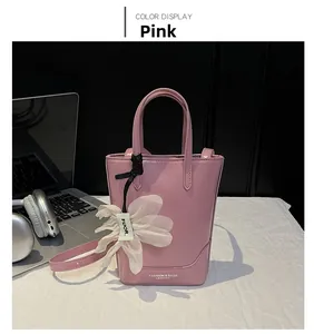 Detail of pink PU leather tote bag with white flower charm and adjustable strap