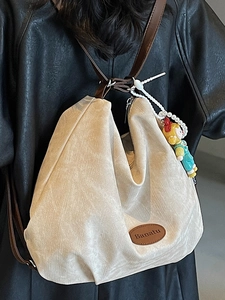 Minimalist beige textured canvas hobo bag with brown leather strap and cartoon pendant