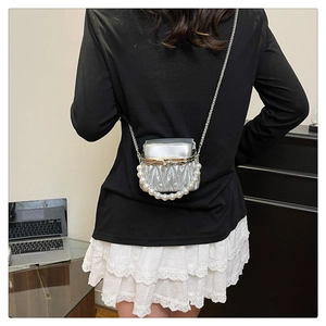 Detail of a silver pleated mini bag with a pearl handle and delicate metal chain strap