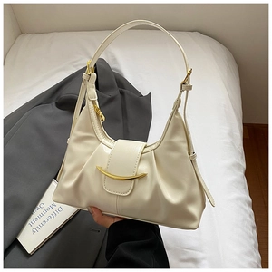 Chic beige underarm bag with gold crescent buckle detail on soft bedding background