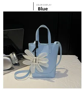 Detail of light blue glossy leather tote bag with white organza daisy charm and silver print
