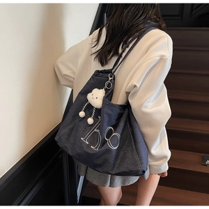 Détail du sac cabas en denim bleu foncé avec broderie et pendentif nuage doux