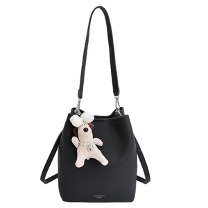 Minimalist black leather bucket bag for women with a cute white puppy plush charm