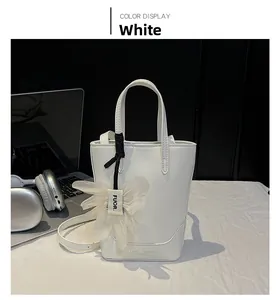 Detail of white leather tote bag with floral charm and subtle textured leather finish