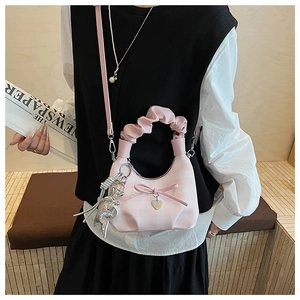 Detail of pink plaid handbag featuring ruffled handle, bow accent, and rabbit charm