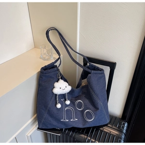 Détail du sac fourre-tout en denim bleu avec broderie blanche et charmant nuage en peluche