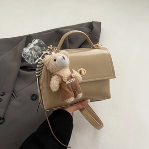 Detail of beige leather crossbody bag with gold twist lock and cute bear charm pendant